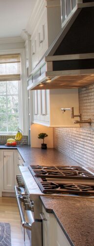 This is a picture of the range and stove in a silver kitchen with custom cabinetry by Kountry Kraft Cabinetry. 