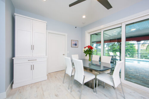 This is a picture of the back dining room with custom white cabinets in the far left corner made by Kountry Kraft Custom Cabinetry.