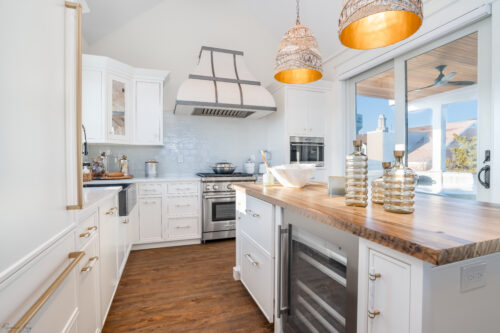 This is a picture of a white kitchen featuring a silver oven and microwave from Wolf with custom cabinetry from Kountry Kraft Cabinetry. 