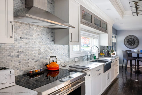 This is a picture of the range/stove along with the gray tile backsplash from a kitchen in Great Neck New York with custom cabinetry by Kountry Kraft Cabinetry.