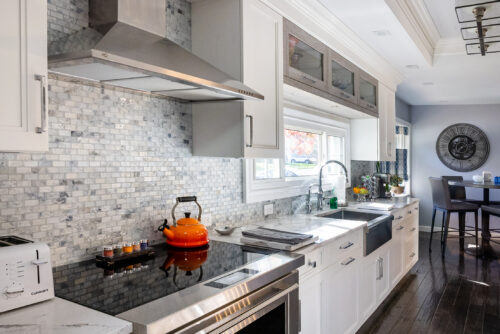 This is a picture of the range/stove along with the gray tile backsplash from a kitchen in Great Neck New York with custom cabinetry by Kountry Kraft Cabinetry. 