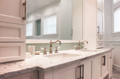 This is a picture showcasing the double sink with a white marble countertop and custom made cabinets by Kountry Kraft Cabinetry. 