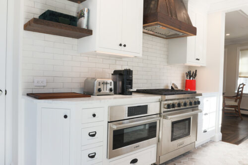 This is a picture of a white kitchen with a Wolf stove and Bosch microwave with custom cabinetry from Kountry Kraft Cabinetry. 