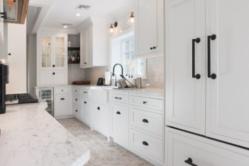 This is a picture of a narrow white kitchen with custom cabinets made by Kountry Kraft Cabinetry. 