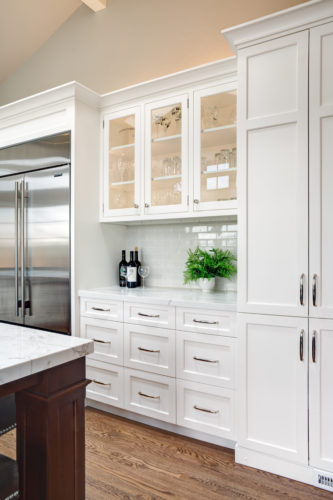 Tall White Kitchen Cabinets Featuring Glass Cabinet Doors and Silver Knobs and Pull Hardware