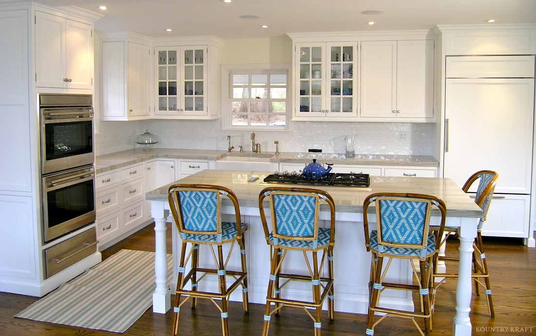 White L-shaped kitchen with ovens, island, cooktop, and four chairs Greenwich, CT