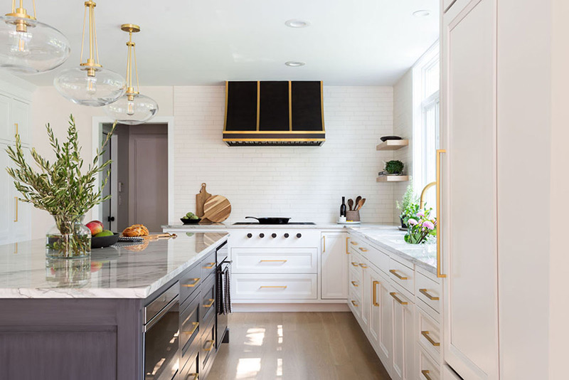 Painted kitchen island design features soft white inset cabinets offset by large dark island. 