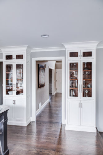 Tall Custom Crafted Cabinets Featuring Glass Doors to Showcase Drinkware in this Transitional Kitchen