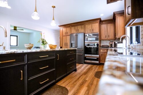 This is a picture including the custom dark gray fridge, microwave, and oven included in the kitchen from Kountry Kraft Custom Cabinetry. 