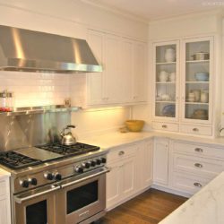 White U-shaped kitchen with stainless steel range and glass panel cabinetry Darien, CT