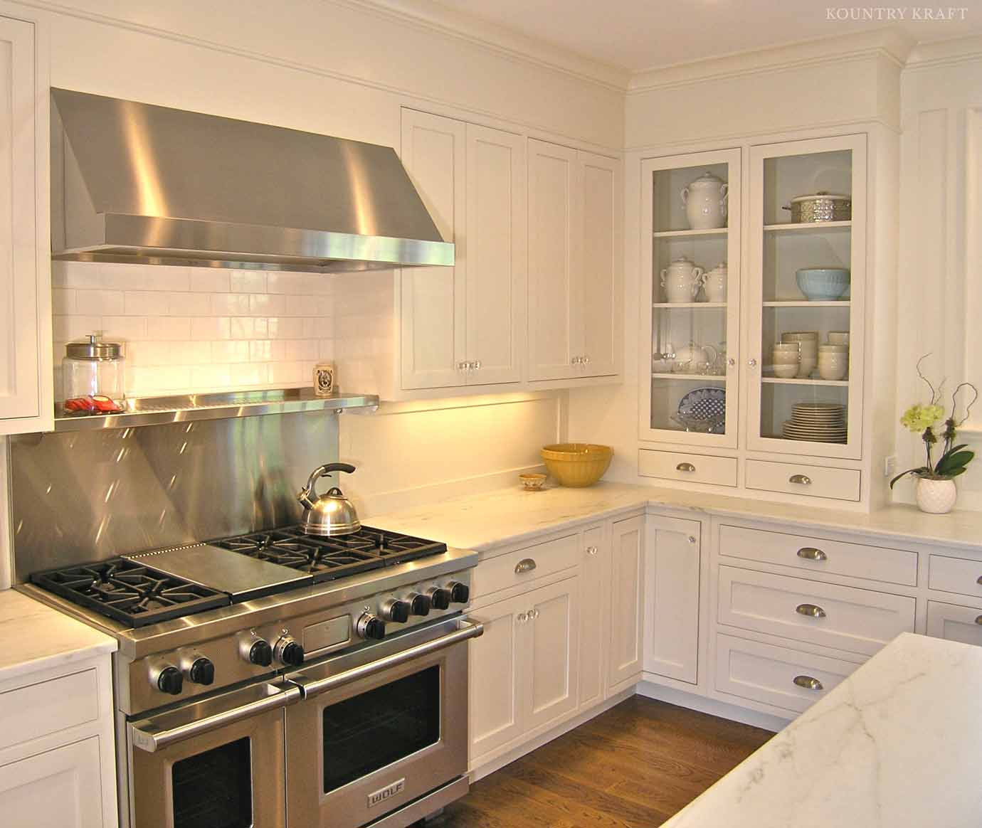 White U-shaped kitchen with stainless steel range and glass panel cabinetry Darien, CT