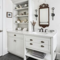 Custom vanity and open shelving in a bathroom remodel in Exeter NH featuring Gray Owl cabinetry, seashell hardware, and coastal accents.
