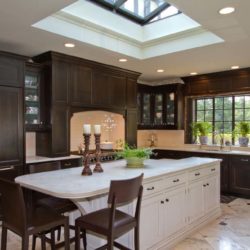 Dark cabinets, white island with three chairs, range, and skylight North Haledon, NJ