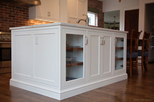 White island with glass panel cabinet door and outlets viewed from an angle Madison, NJ