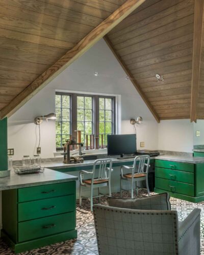 Custom cabinets in Haverford PA at a desk-height workspace, featuring green drawers, a monitor setup, and patterned floor tiles.