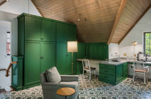 Craft room view with tall storage cabinets in Haverford PA, green cabinetry, vaulted ceiling, and lounge chair creating a versatile office space.
