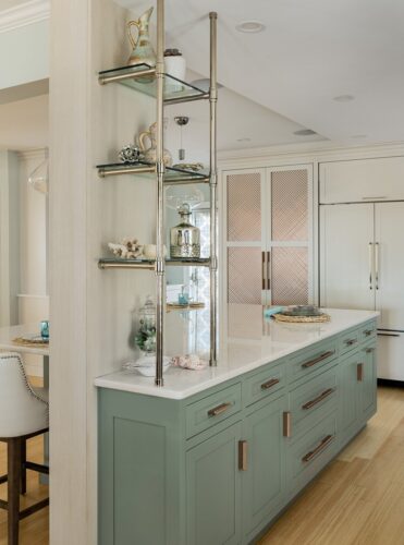Greyhound painted kitchen island with rose-gold hardware and glass shelving in a Massachusetts home with custom cabinets.