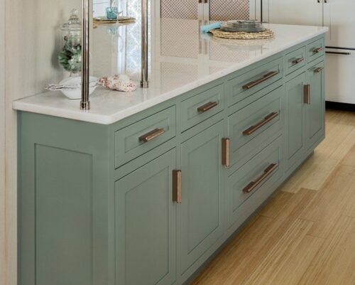 Close-up of Greyhound island cabinetry with rose-gold hardware and marble countertop in a Massachusetts kitchen with custom cabinets.