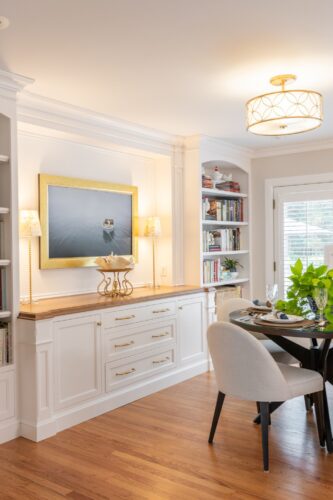 Custom entertainment cabinetry Cheshire CT featuring white cabinetry, built-ins, arched shelving, and warm wood counters in a dining and game room design.