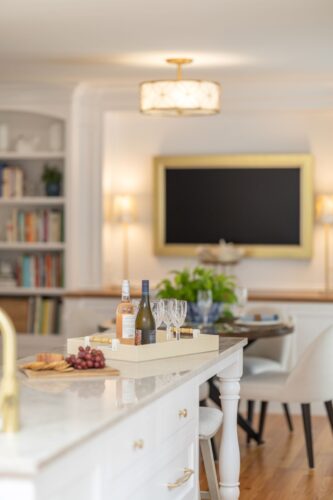 Custom entertainment cabinetry Cheshire CT featuring white cabinetry, built-ins, arched shelving, and warm wood counters in a dining and game room design.