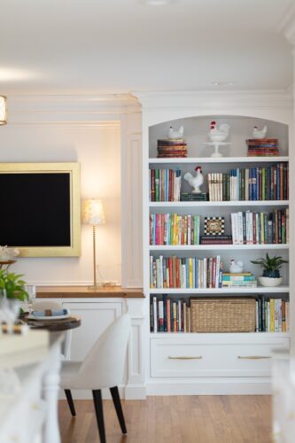 Custom entertainment cabinetry Cheshire CT featuring white cabinetry, built-ins, arched shelving, and warm wood counters in a dining and game room design.