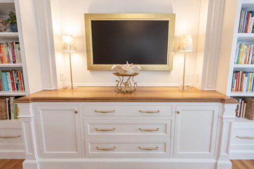 Custom entertainment cabinetry Cheshire CT featuring white cabinetry, built-ins, arched shelving, and warm wood counters in a dining and game room design.