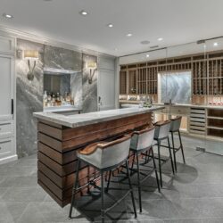 Custom home bar cabinets in Villanova, PA featuring a cherry island with Cocoa Brown/English Walnut stain and tall maple cabinets painted Metallic Silver by Benjamin Moore.