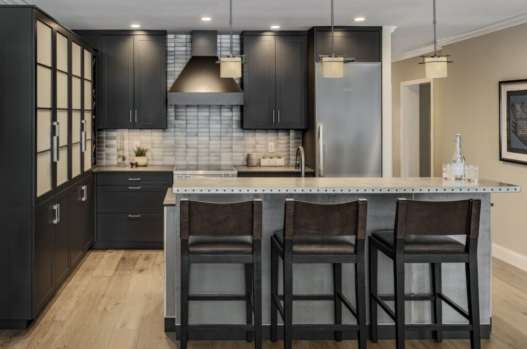 Modern kitchen with custom kitchen cabinets in Exeter NH featuring black cabinetry, stainless steel island, and wood flooring. Modern kitchen with custom kitchen cabinets in Exeter NH featuring black cabinetry, stainless steel island, and wood flooring.