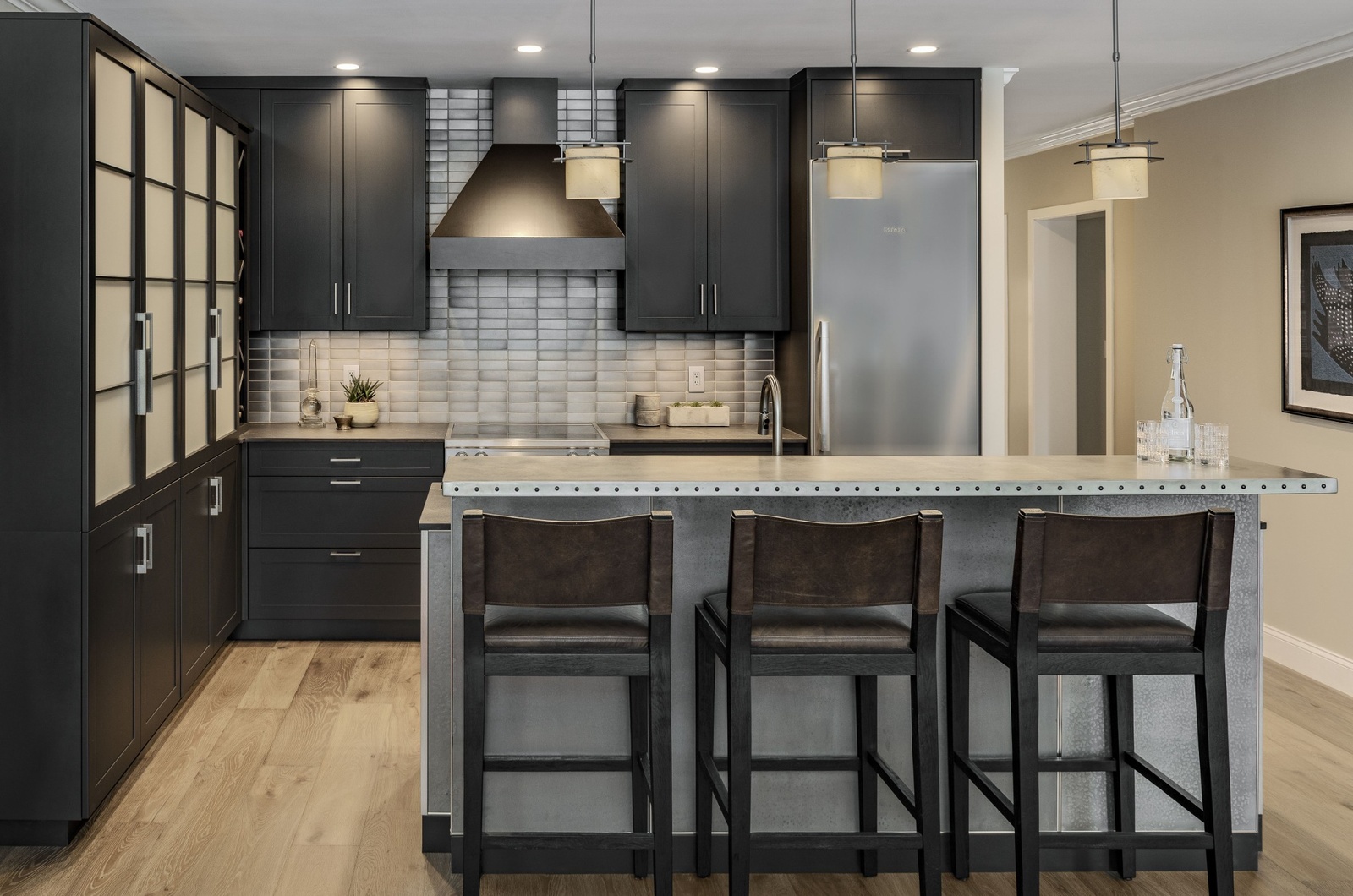 Modern kitchen with custom kitchen cabinets in Exeter NH featuring black cabinetry, stainless steel island, and wood flooring.