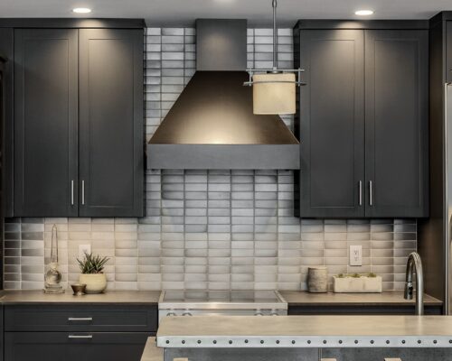 Black range hood with surrounding custom kitchen cabinets Exeter NH and gray tiled backsplash for a modern look.