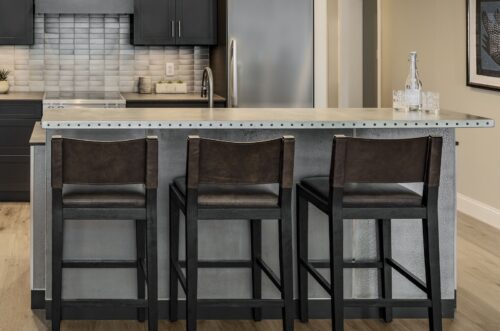 Industrial-inspired island with riveted countertop and bar seating, paired with custom kitchen cabinets in Exeter NH.