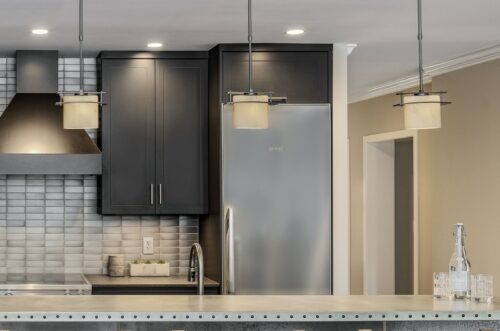 Pendant lighting over island highlighting custom kitchen cabinets Exeter NH in black maple with stainless finishes.
