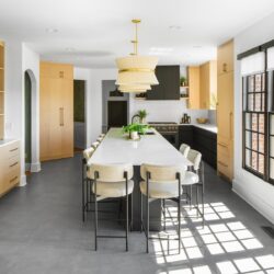 Custom kitchen cabinets Knoxville TN – wide view of kitchen with large island, light wood cabinetry, and black-framed windows.