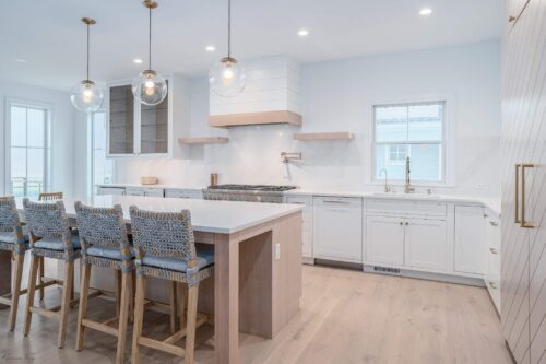 Coastal-inspired Avalon NJ kitchen featuring custom cabinets, quartz countertops, Thermador range, and rope-woven bar stools at the island.