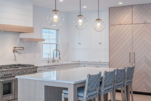 Wide view of Avalon NJ kitchen remodel with custom maple and oak cabinetry, pendant lights, quartz counters, and chevron wood design.