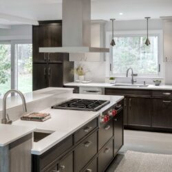 Modern kitchen featuring custom kitchen cabinets in Exeter NH with a large island, quartz countertops, and stainless steel hood.
