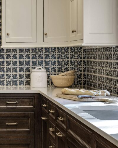 Close-up of custom kitchen cabinets in Exeter NH with white upper cabinets, walnut base cabinets, and decorative navy backsplash tile.