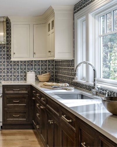 Sink area of custom kitchen cabinets in Exeter NH with large window, polished chrome faucet, and walnut base cabinetry by Kountry Kraft.