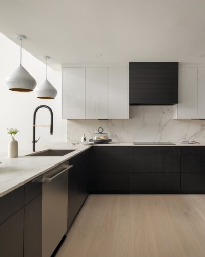 Modern kitchen with custom kitchen cabinets Ludlow VT featuring black lower cabinetry, white uppers, and marble backsplash.