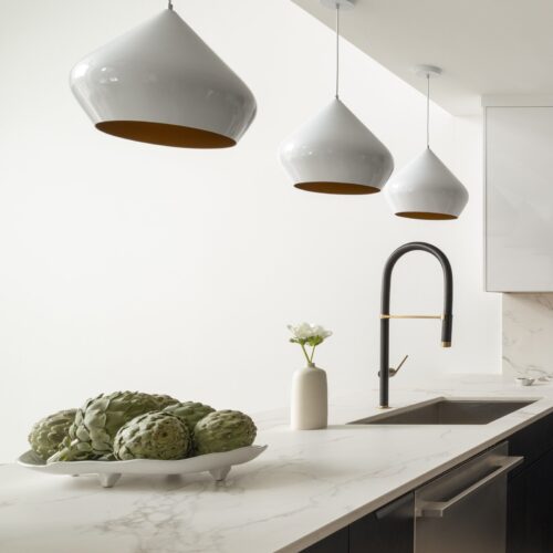 Minimalist kitchen island with custom cabinets Ludlow VT, decorated with fresh artichokes and modern pendant lights.