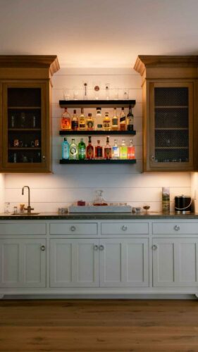 A wet bar with bar sink and custom metal counter with cabinet lighting