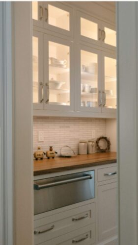 A butler pantry with wood countertop warming drawer a in cabinet lighting