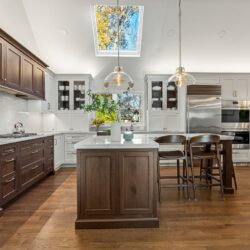 Custom kitchen Short Hills NJ with white perimeter cabinetry, walnut island and range hood.