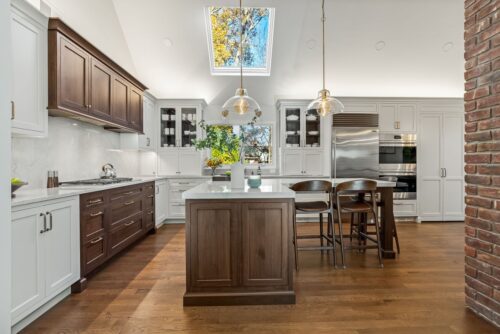 Custom kitchen Short Hills NJ with white perimeter cabinetry, walnut island and range hood.
