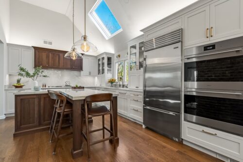 Custom kitchen Short Hills NJ with white perimeter cabinetry, walnut island and range hood.