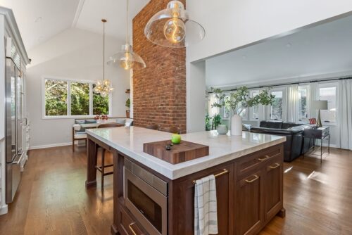 Custom kitchen Short Hills NJ with white perimeter cabinetry, walnut island with microwave drawer and white countertops.