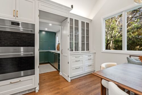 Custom kitchen Short Hills NJ with white perimeter cabinetry and opening to a butler's pantry with green cabinetry.