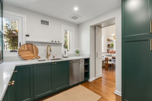Custom kitchen Short Hills NJ picture showing butler's pantry with green painted cabinetry and honey bronze fixtures. There is a sink and dishwasher.