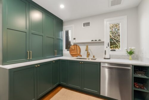 Custom kitchen Short Hills NJ picture showing butler's pantry with green painted cabinetry and honey bronze fixtures. There is a sink and dishwasher.
