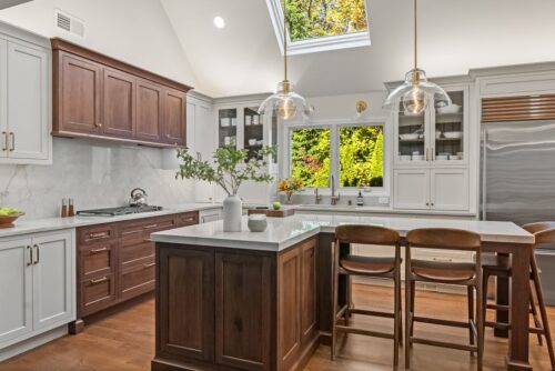 Custom kitchen Short Hills NJ with white perimeter cabinetry, walnut island and range hood.